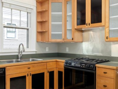 Bright modern kitchen featuring wooden cabinets, oven, and stainless steel sink.